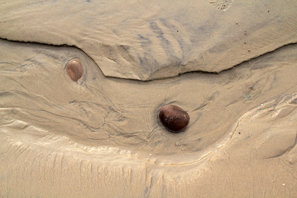 two rocks sticking out of the sand on a beach