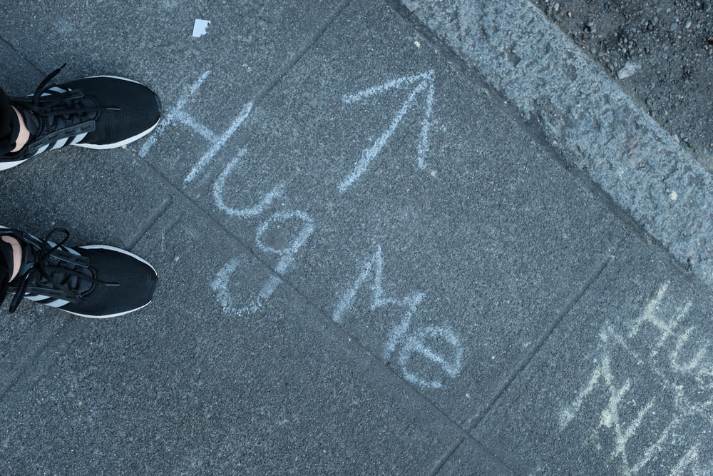 a person standing in front of a sidewalk with chalk writing on it