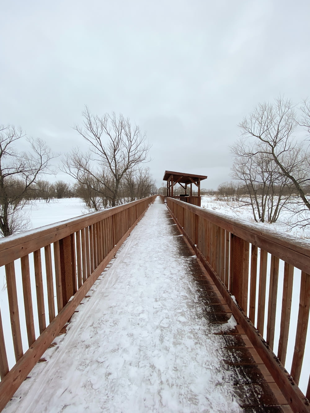 a wooden bridge with snow on the ground