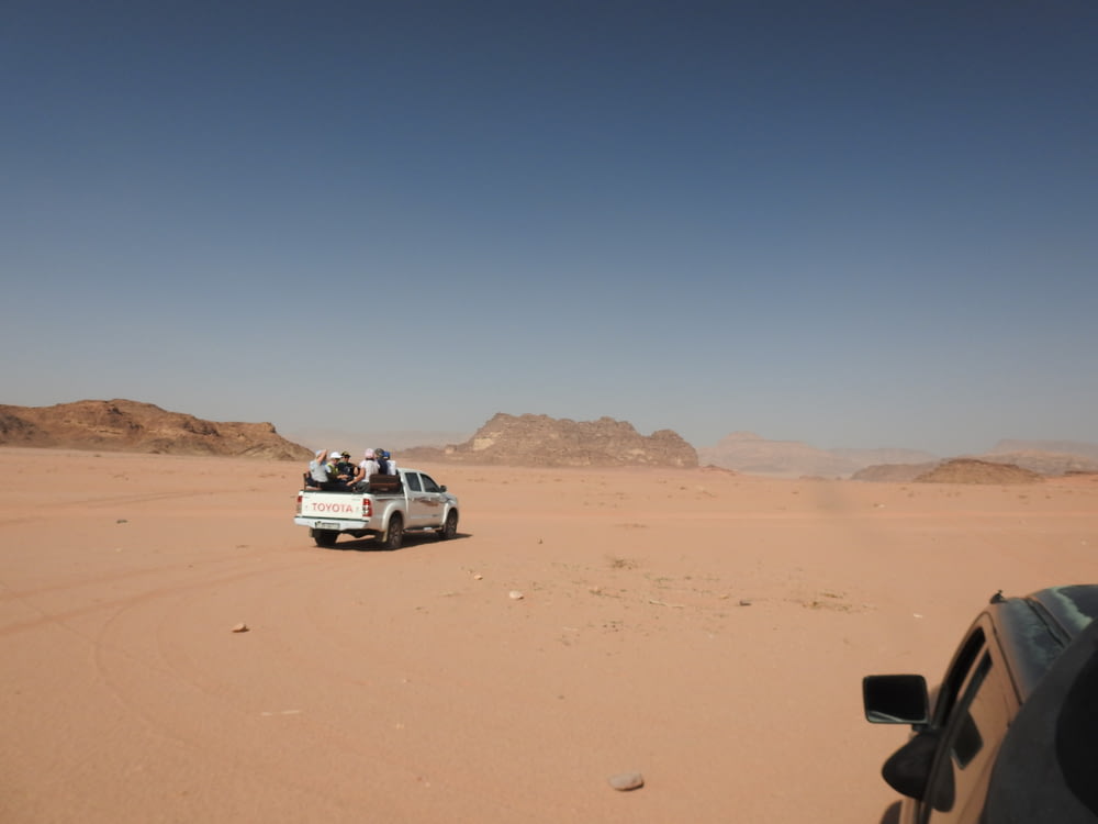 a car driving through the desert with people in the back