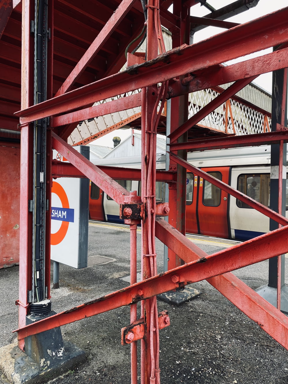 a red metal structure with a train in the background