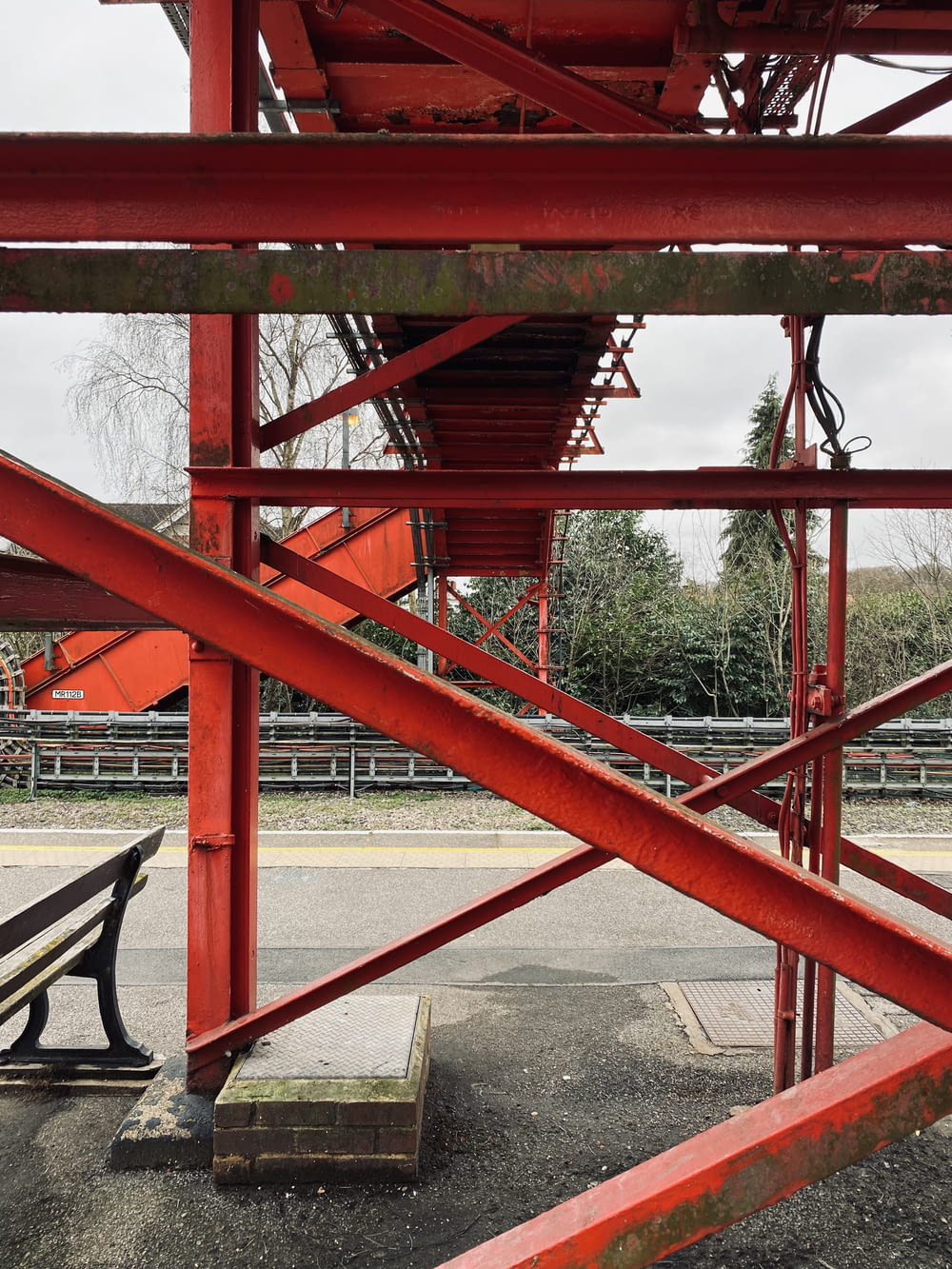 a red metal structure with a bench underneath it