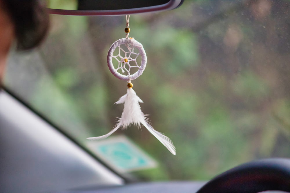 a car dashboard with a white dream catcher hanging from it's side window