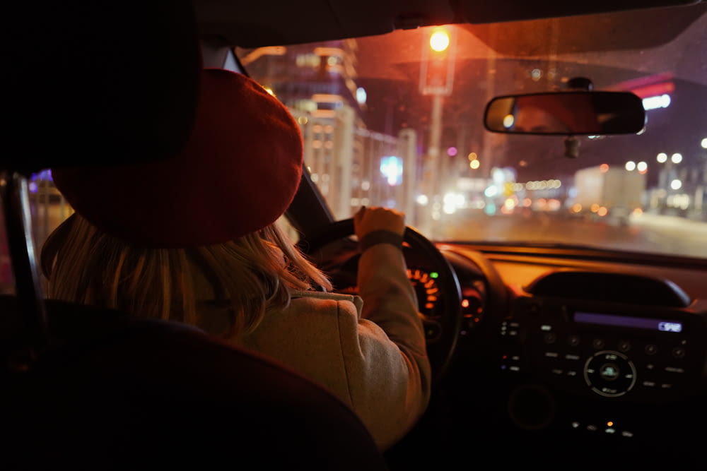 街の通りで夜に車を運転する女性