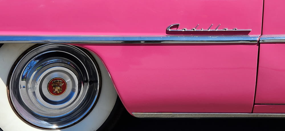 a close up of a pink car with chrome rims