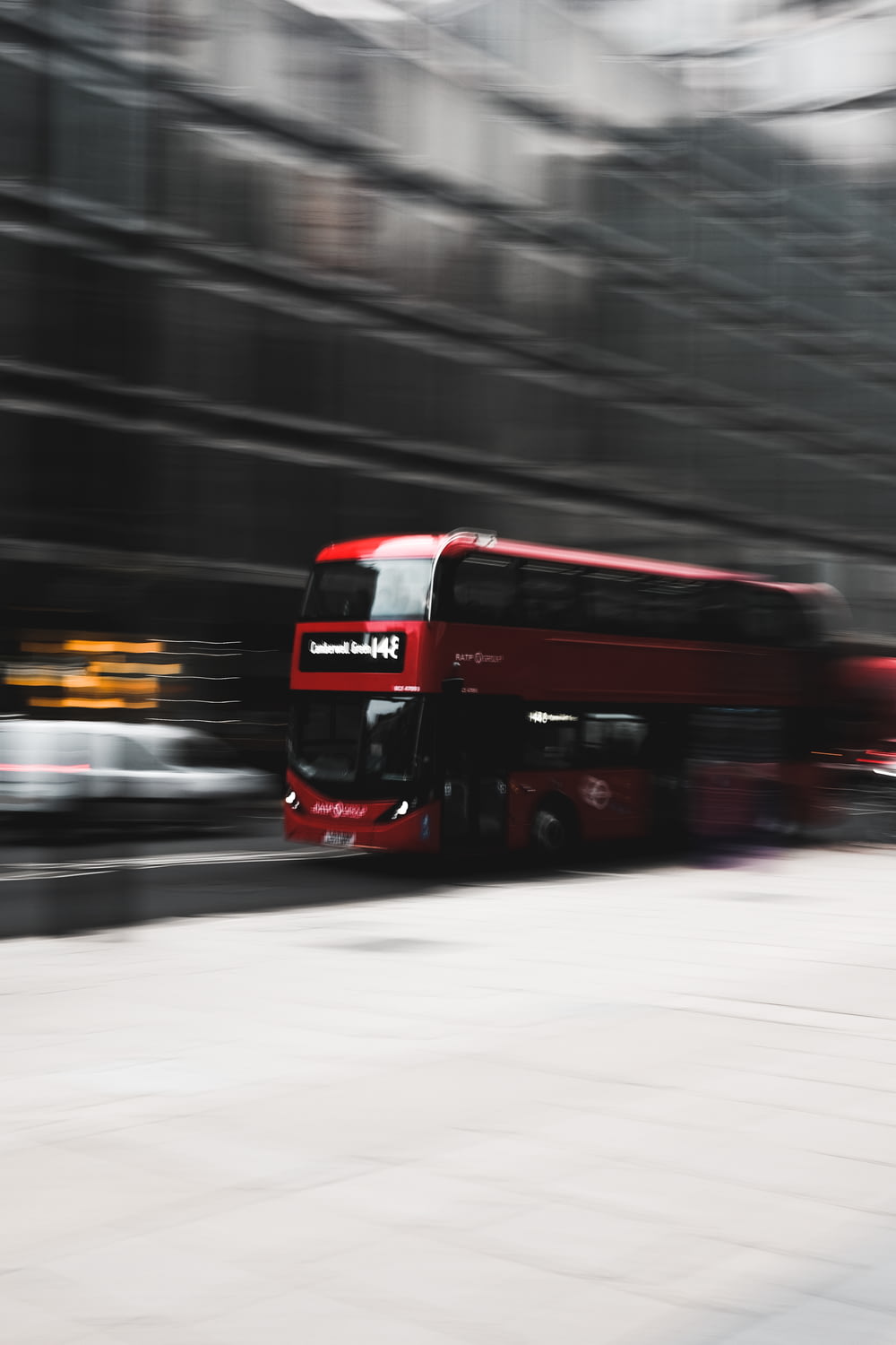 a red bus driving down a street next to a tall building