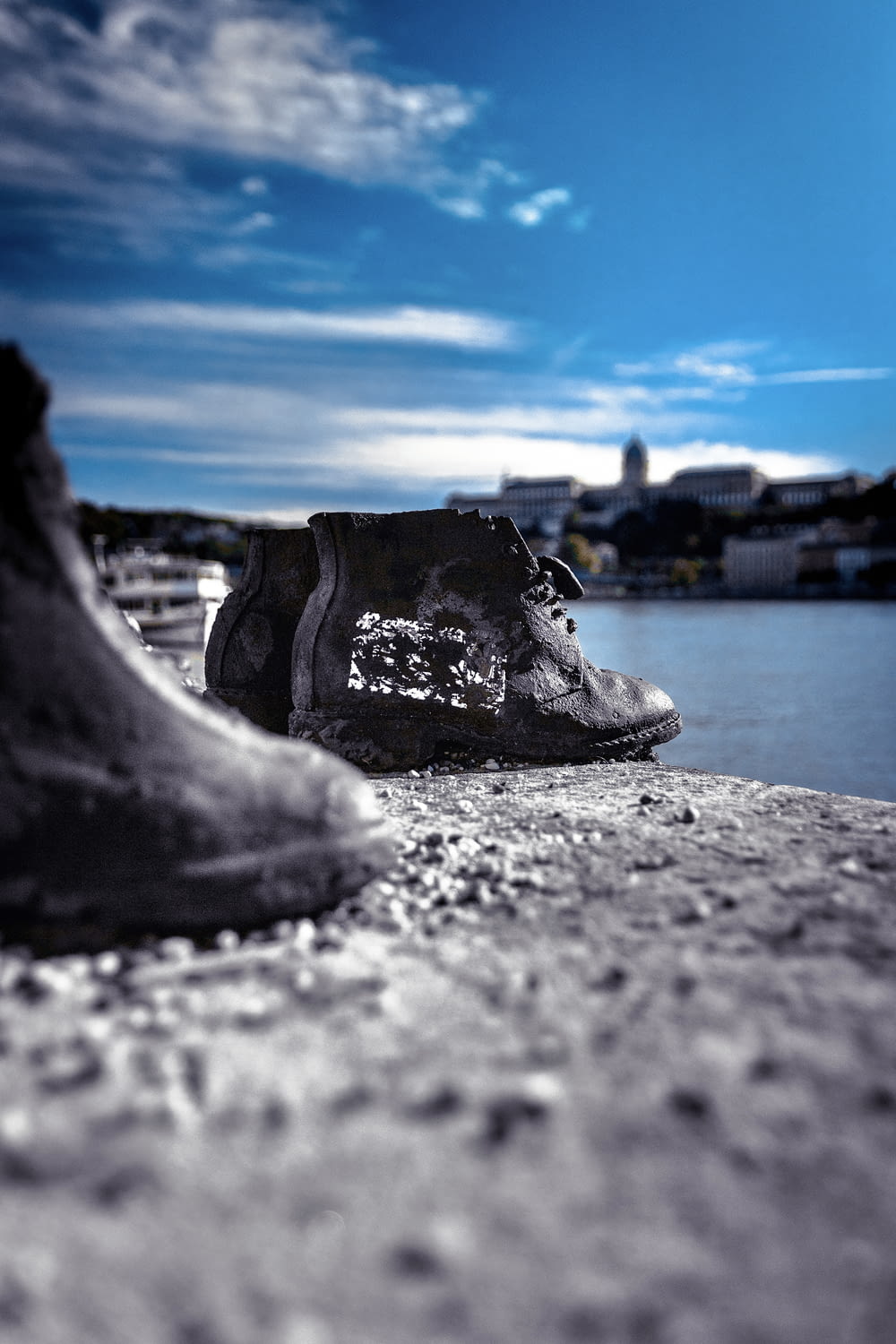 a pair of shoes sitting on the ground next to a body of water