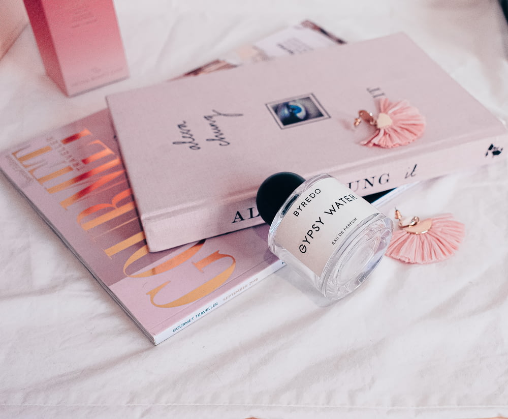 un flacon de parfum posé sur un lit à côté d’un livre