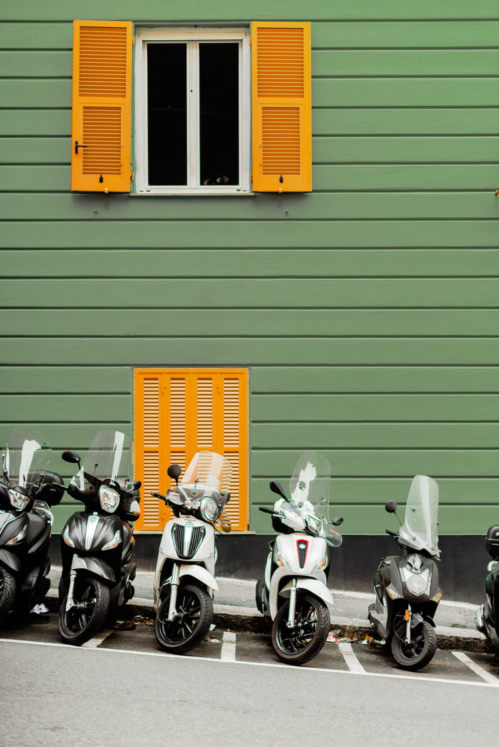 a row of motorcycles parked in front of a green building