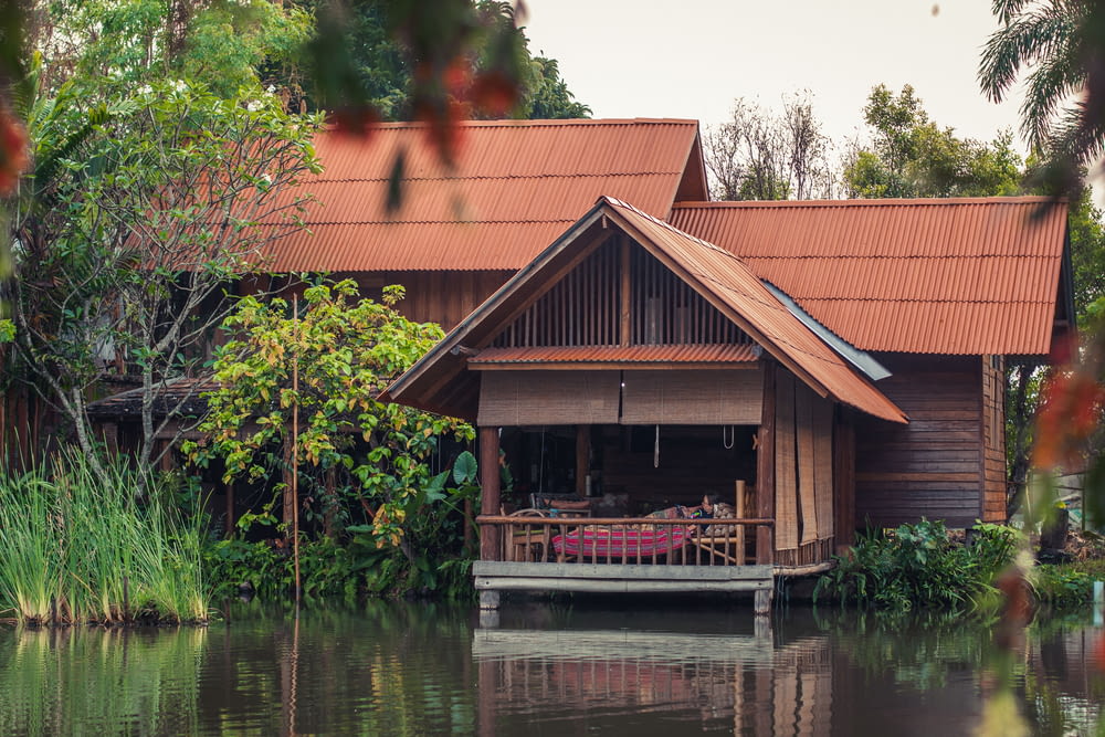 a house sitting on top of a lake next to a lush green forest