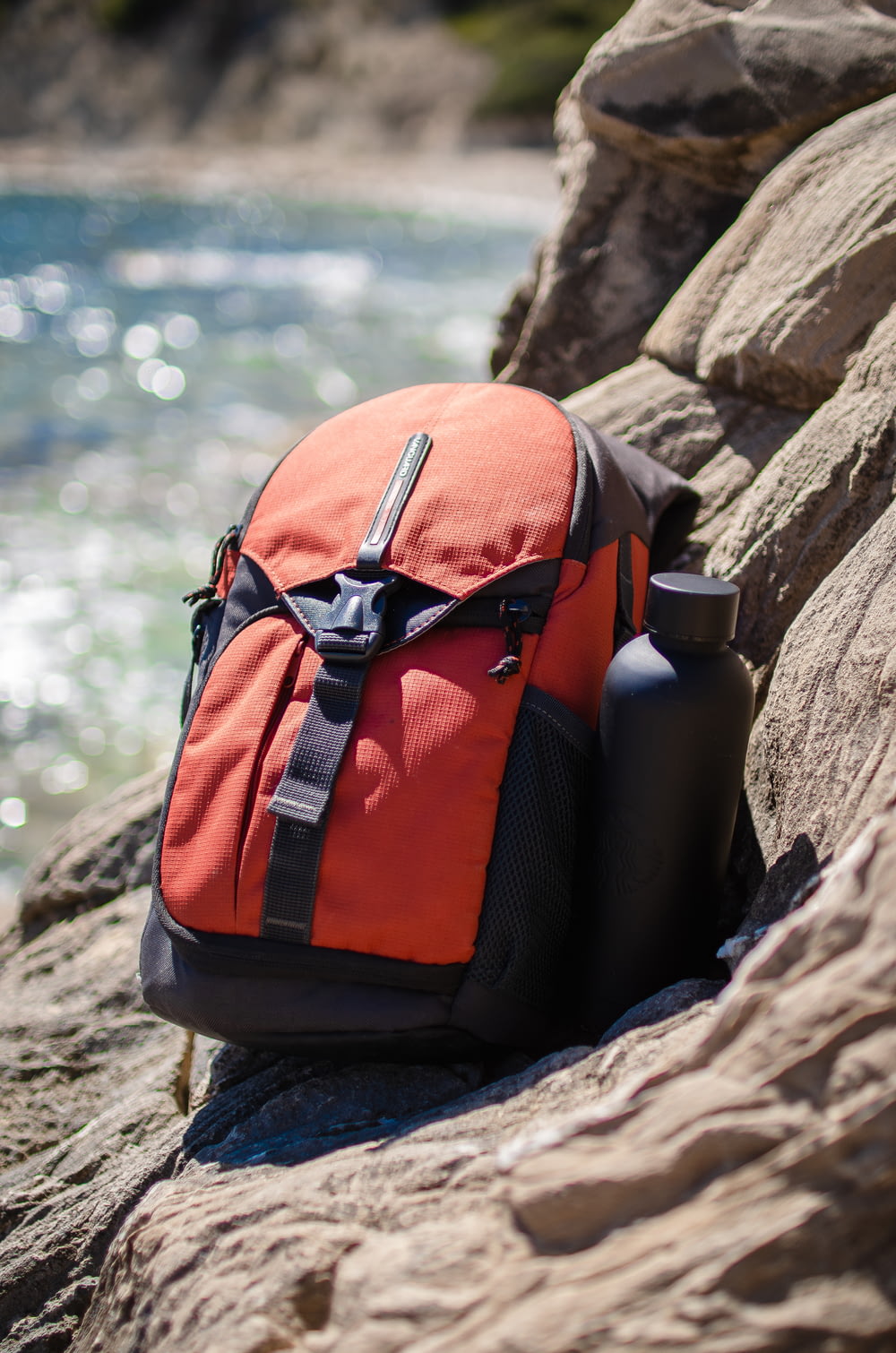 a backpack sitting on a rock next to a body of water