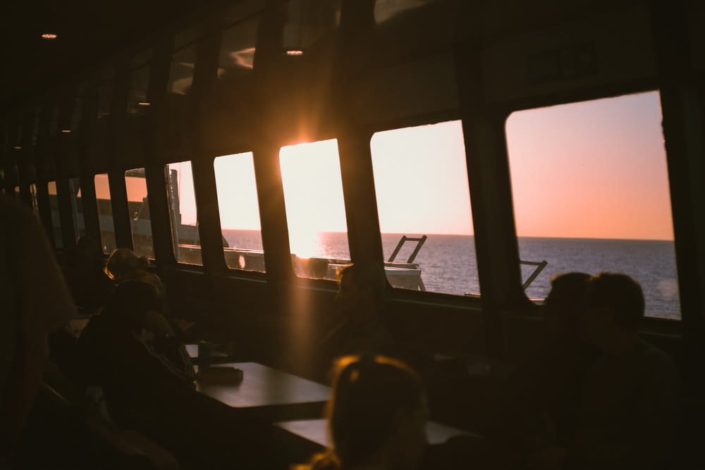 a group of people sitting on a train next to the ocean