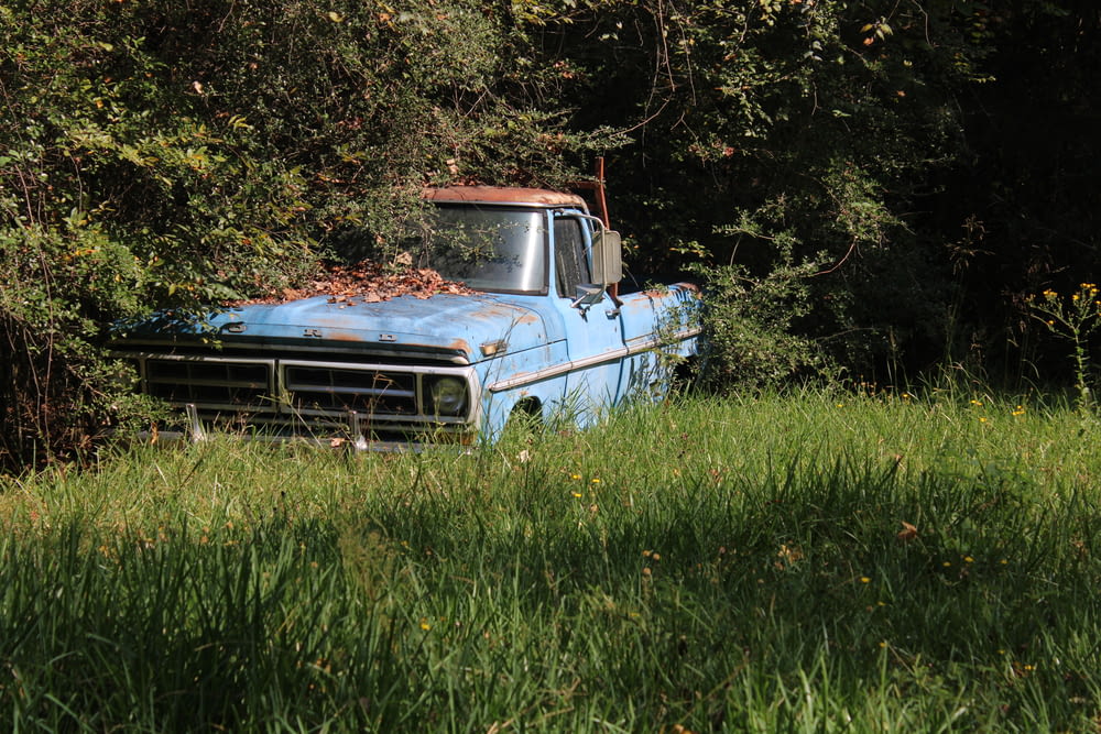 Un vecchio camion blu seduto in mezzo a un campo
