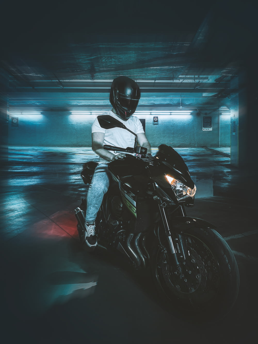 a person sitting on a motorcycle in a parking garage