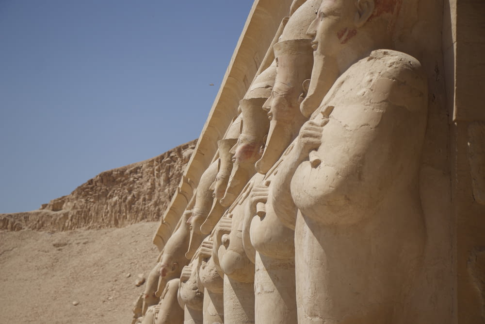 Una hilera de estatuas frente a una pirámide