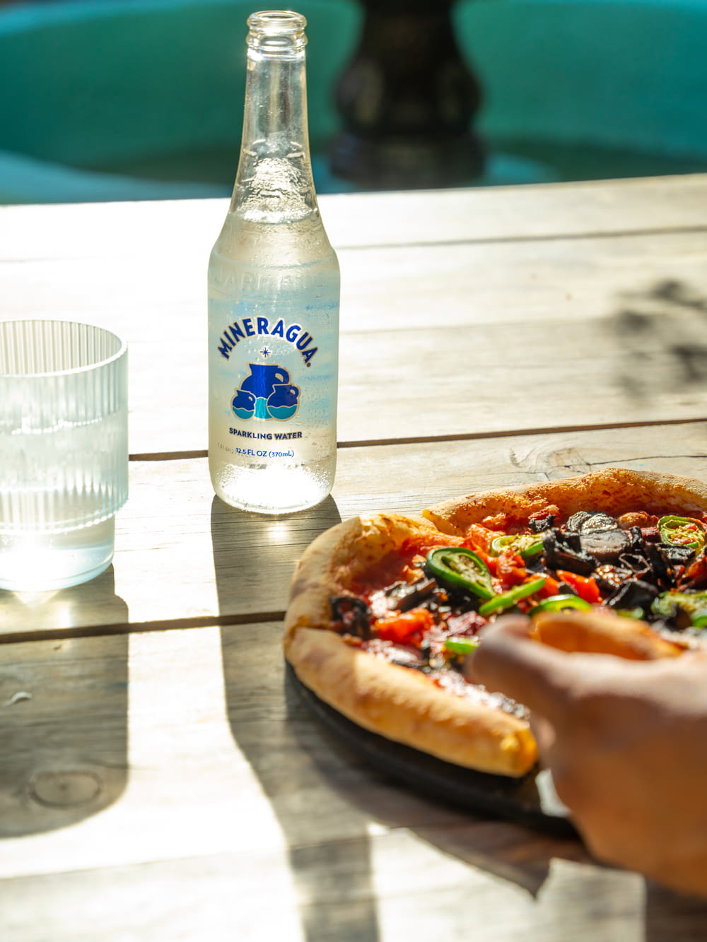 a pizza sitting on top of a wooden table next to a bottle of water
