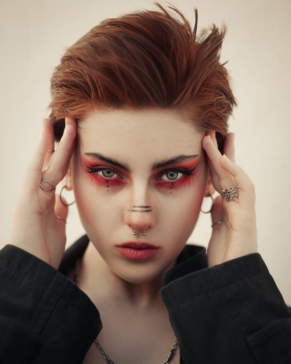 a woman with red makeup and piercings on her face