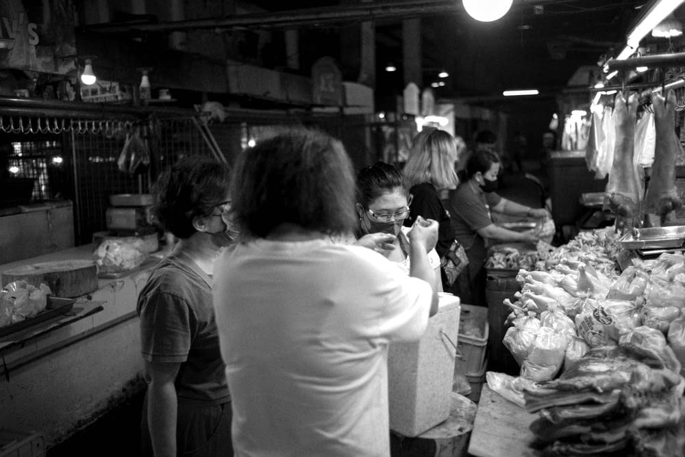 a black and white photo of people shopping in a market
