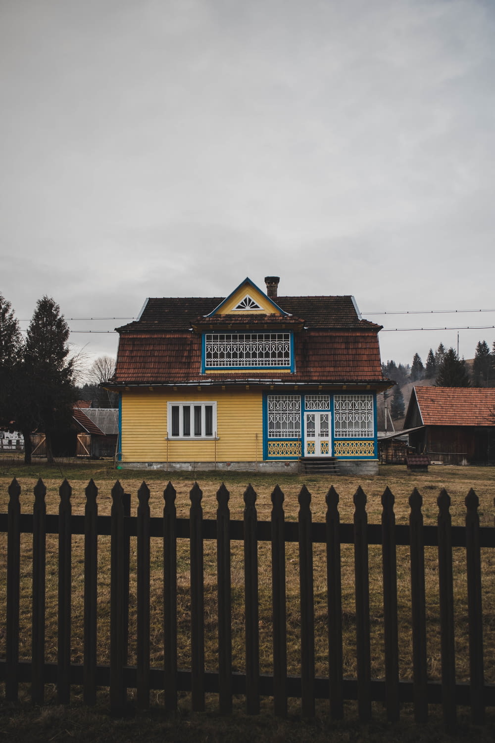a yellow and blue house with a black fence