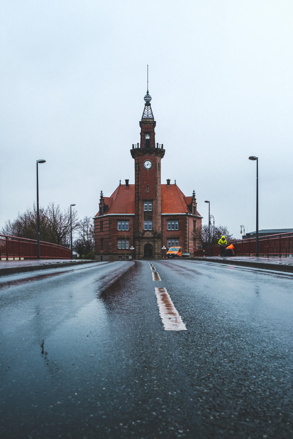 a wet street with a clock tower in the background