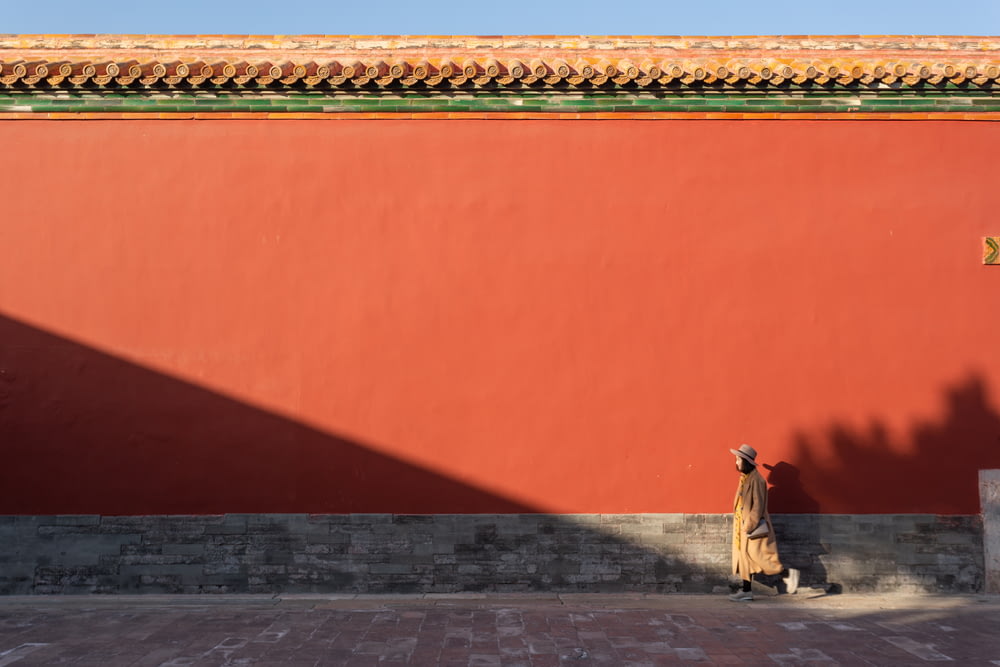 붉은 벽을 지나 거리를 걷고 있는 여자