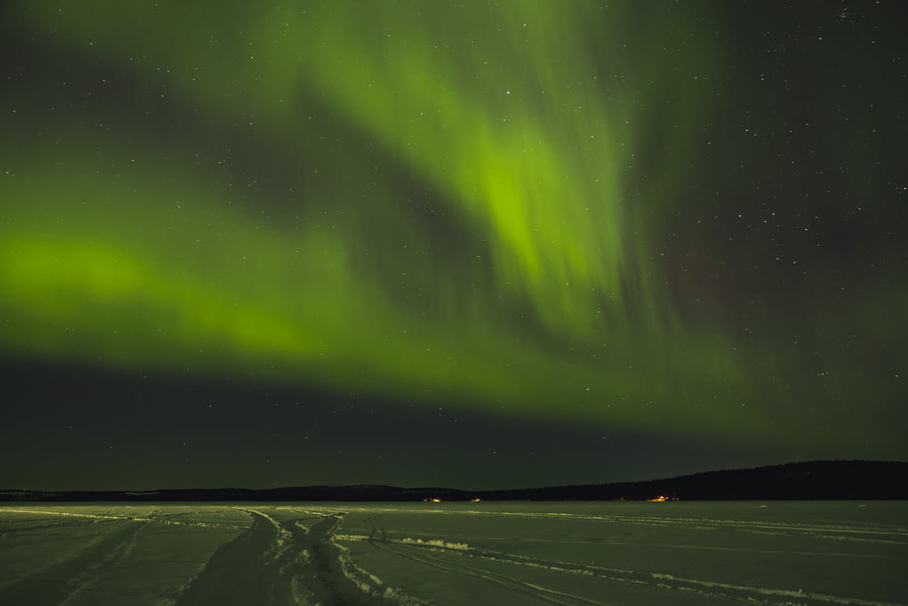 a green aurora bore in the sky above a snow covered field