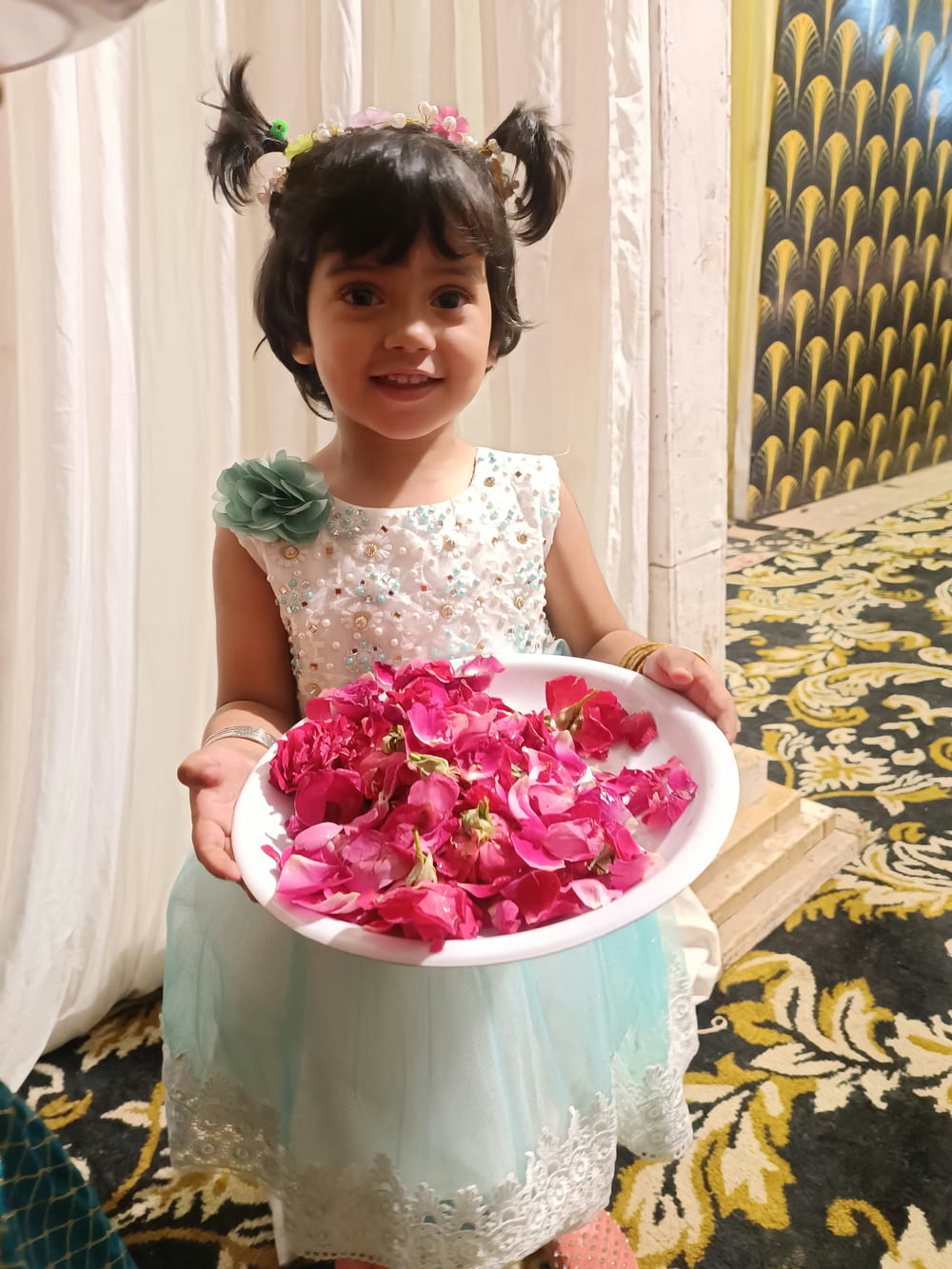 a little girl holding a bowl of flowers