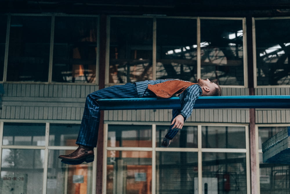 a man laying on a blue bench in front of a building