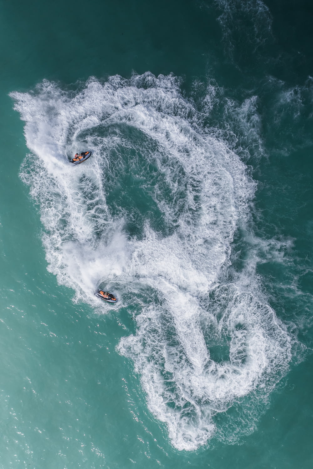 a couple of people riding on top of a wave in the ocean
