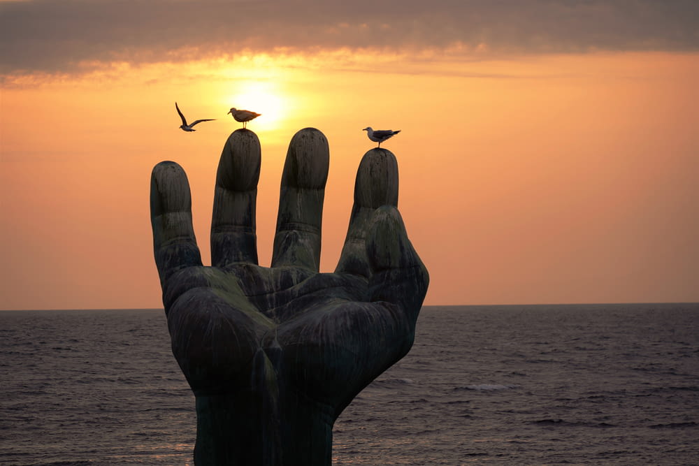 a statue of a hand with two birds on top of it