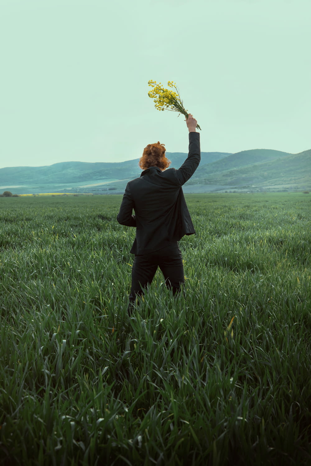 a person in a field holding a bunch of flowers