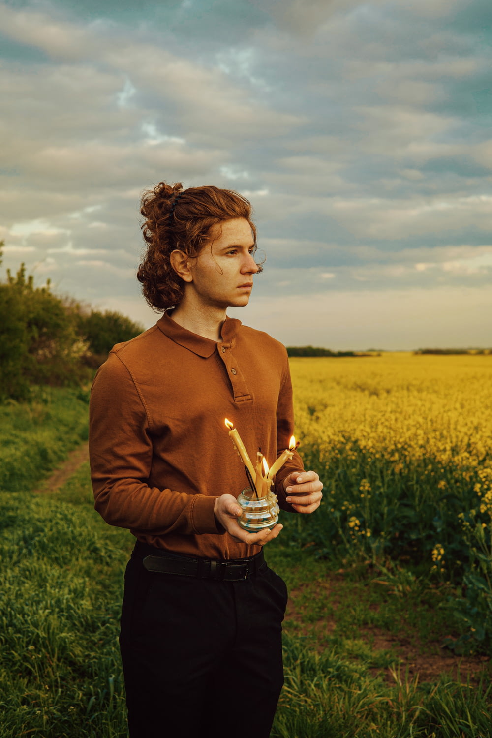a man standing in a field holding a candle