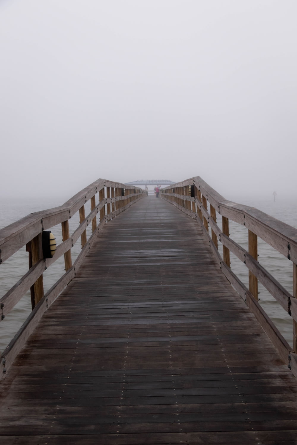a long wooden pier with a foggy sky in the background