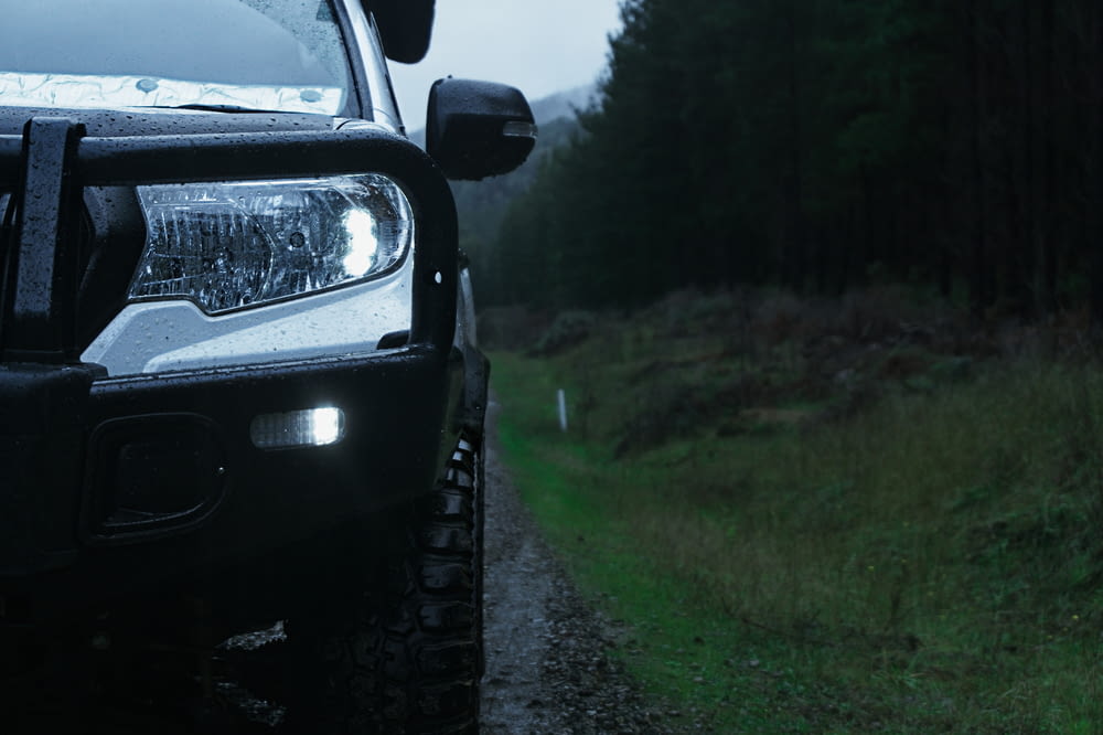 a black truck parked on a dirt road next to a forest
