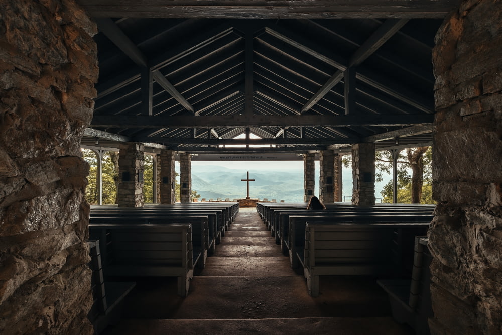 uma igreja vazia com bancos e uma cruz