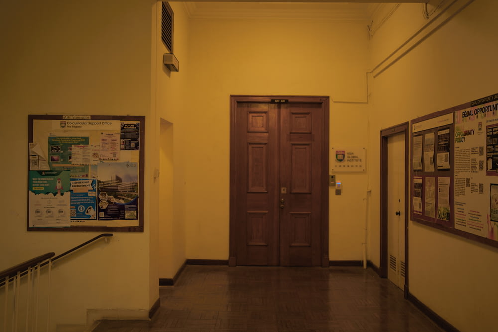 a hallway with a wooden door and posters on the wall