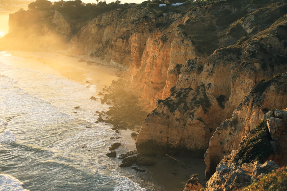 a view of a beach and cliffs at sunset