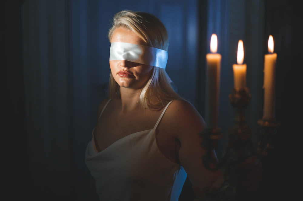 a woman wearing a blindfold in front of a candle