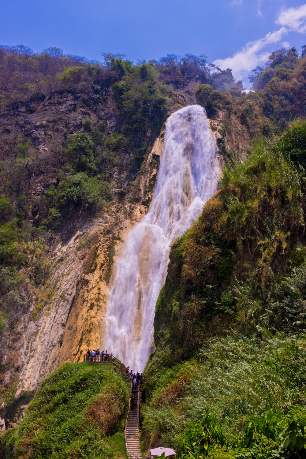 um grupo de pessoas em pé na base de uma cachoeira