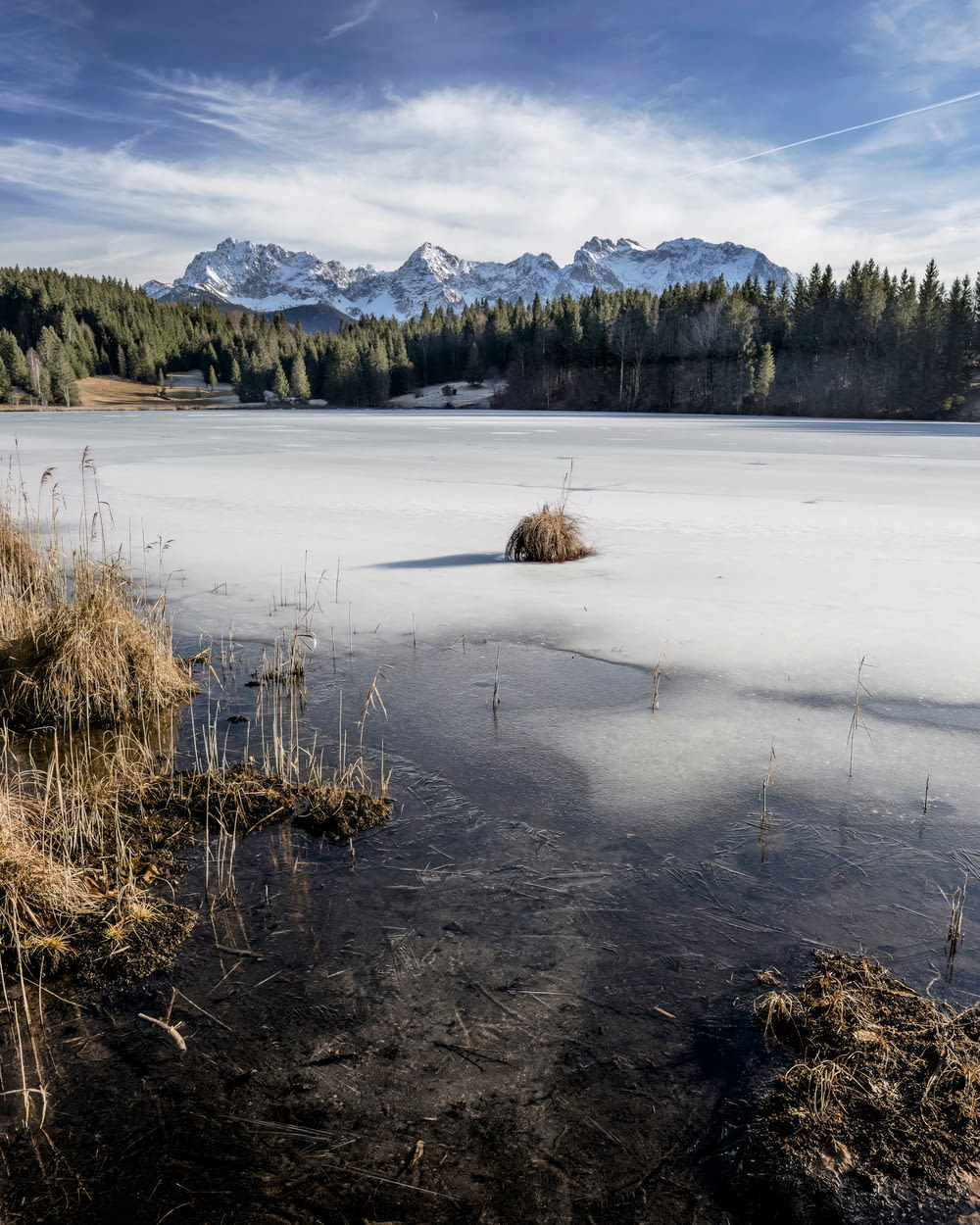 a frozen lake surrounded by trees and mountains