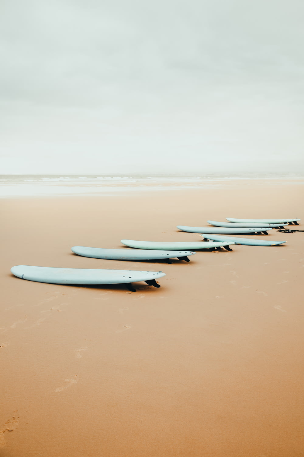 a row of surfboards sitting on top of a sandy beach