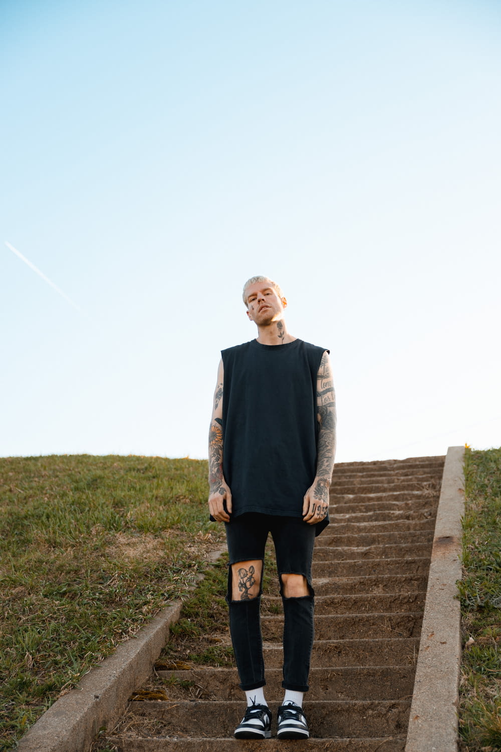 a man with tattoos standing on a set of stairs