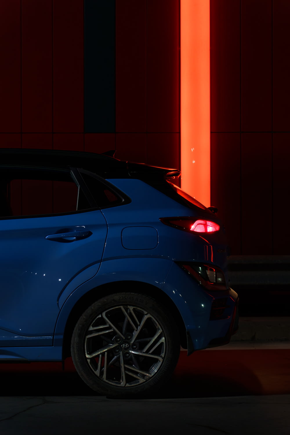 a blue car parked in front of a red wall