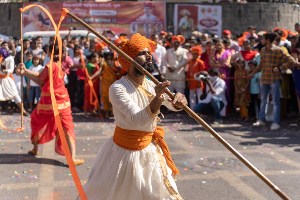 a man in a turban holding a stick in front of a crowd