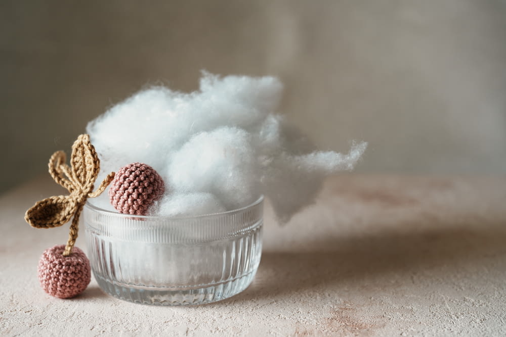 a glass bowl filled with cotton next to a cotton ball