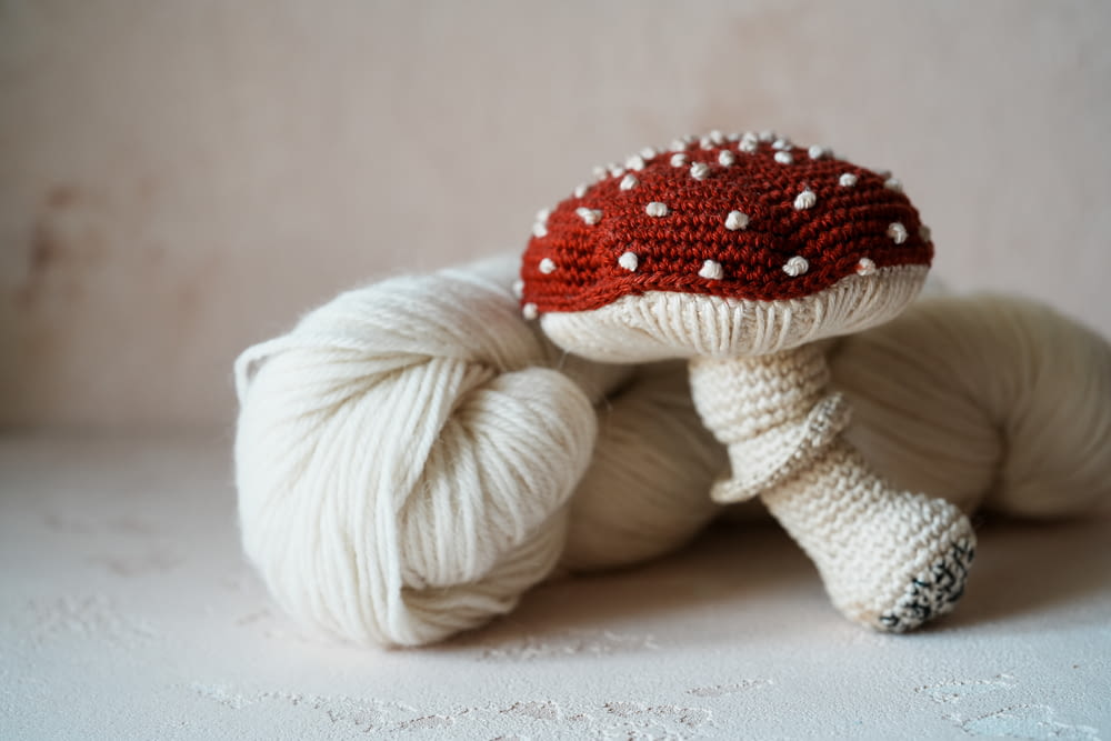 a white ball of yarn with a red mushroom on top of it