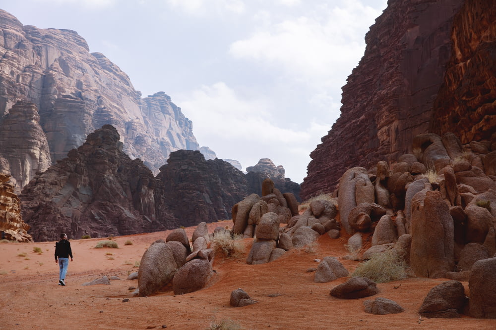 a person walking through a desert area with large rocks
