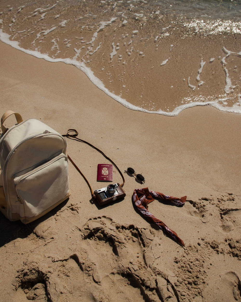a backpack and other items lay on the sand of a beach