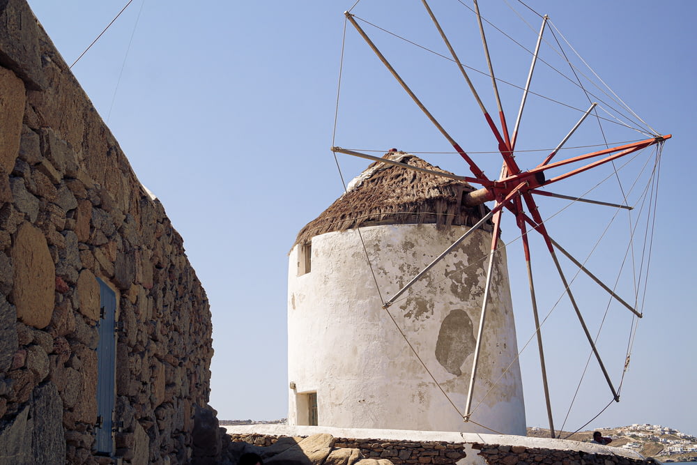 a white and red windmill next to a stone wall