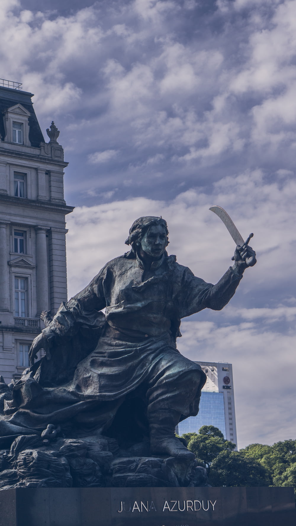 a statue of a man holding a sword in front of a building